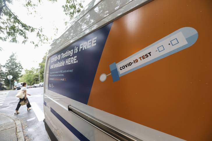 A pedestrian walks past a van for COVID-19 test service near a temporary test site in Sunset Park, Brooklyn on August 13th, 2020.
